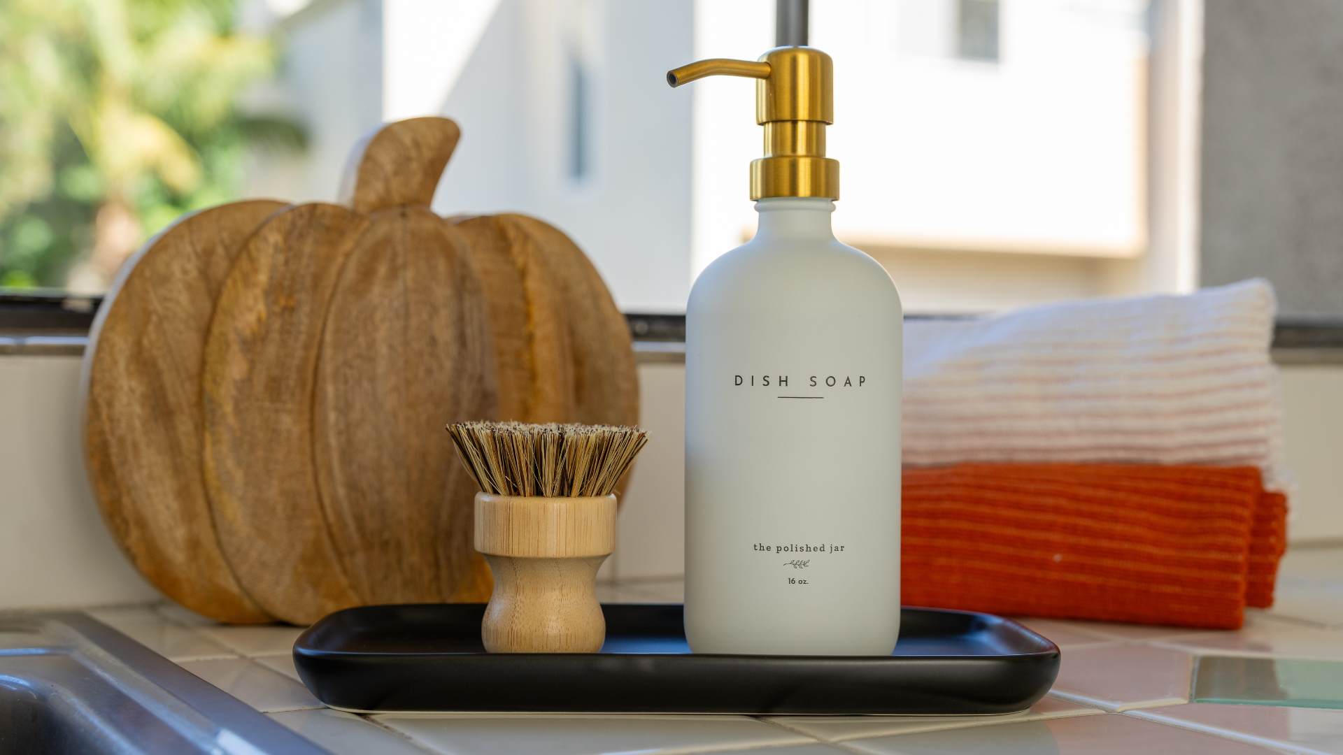 Soap bottle dispenser on a tray with wood pumpkin on the background