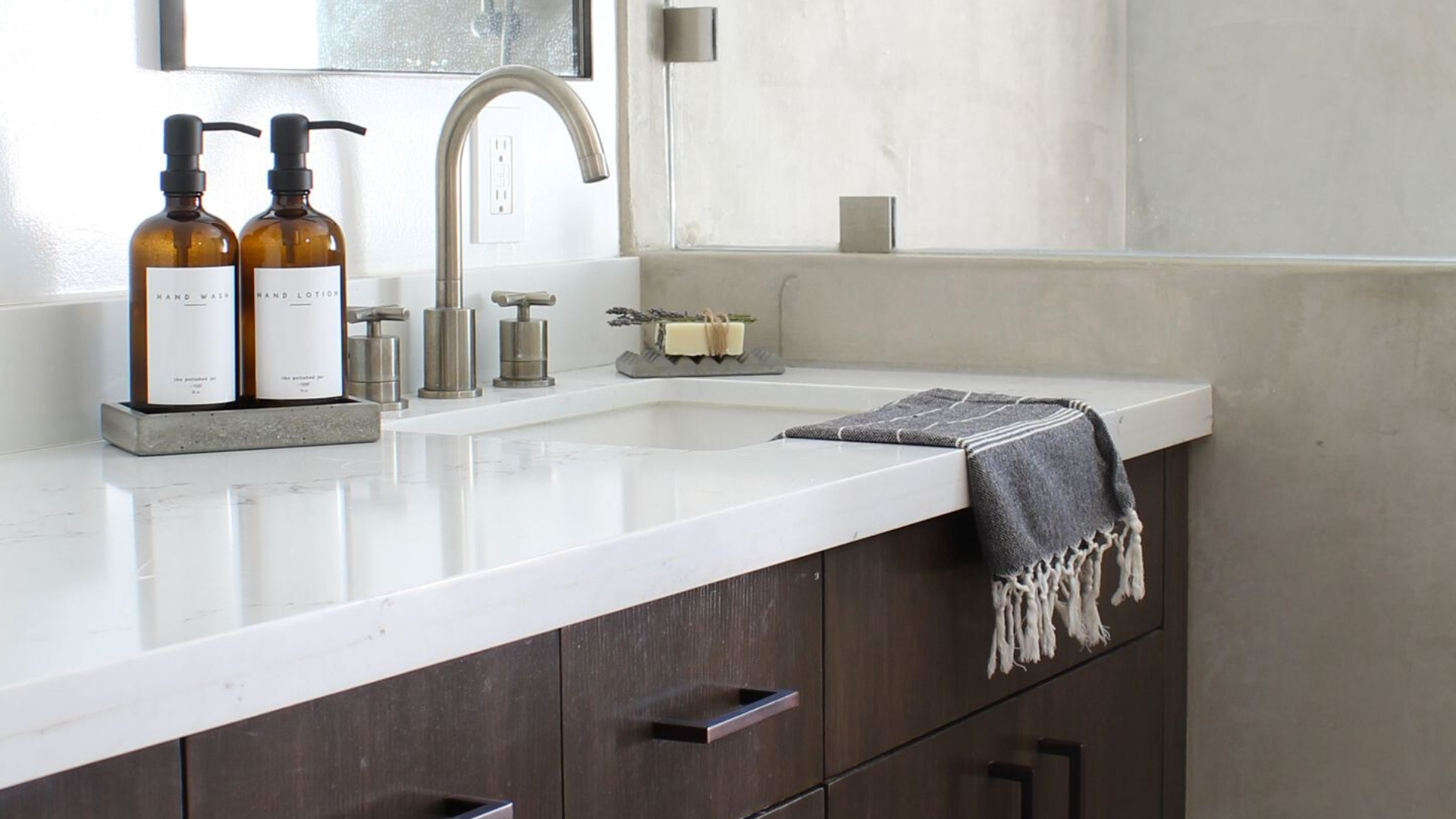 White Bathroom Counter With Silver Faucet and The Polished Jar Bottle Dispensers