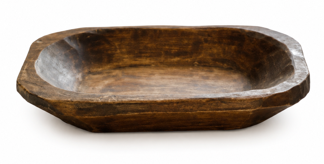 A rustic dark brown wooden bowl with a hand-hewn, octagonal shape, photographed on a clean white background.