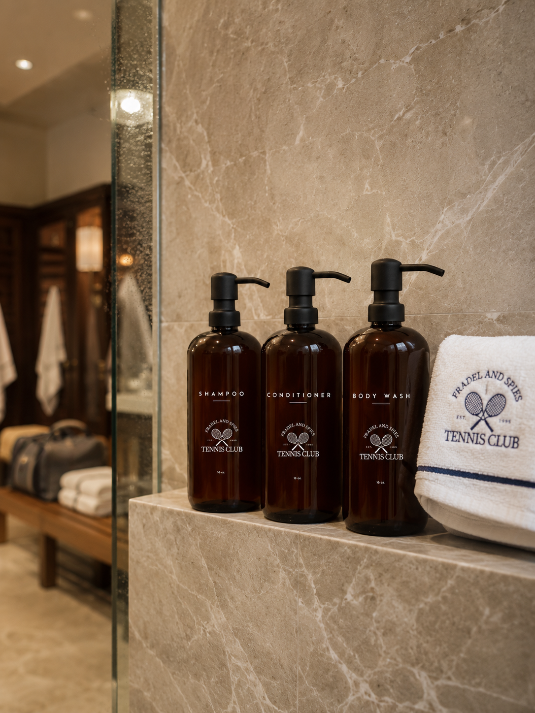 Three brown bottles with pump dispensers on a marble surface, with a towel and bench in the background.