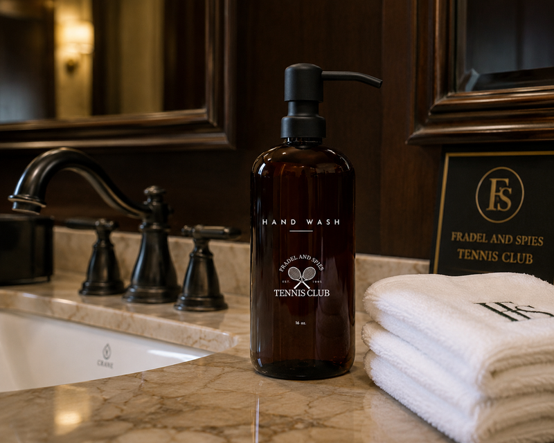 Hand wash bottle and towels on a bathroom counter with a mirror in the background