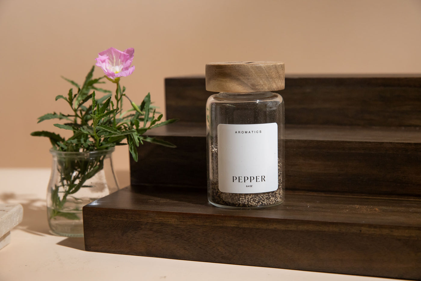 Jar of pepper on a wooden shelf with a flower in the background