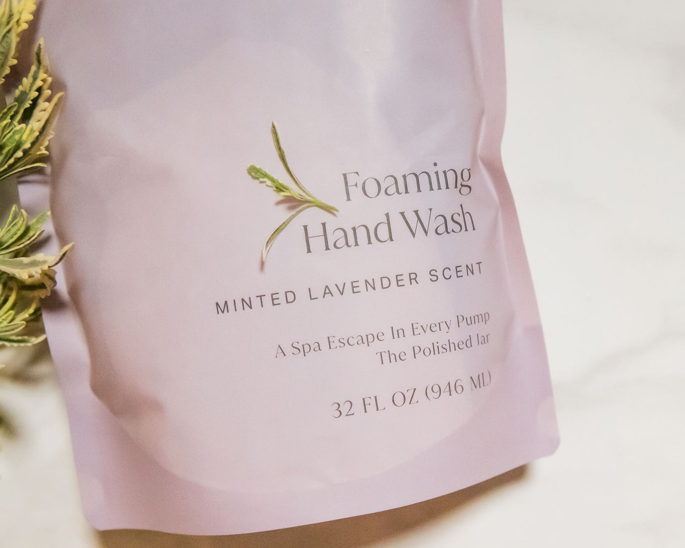 Foaming hand wash packaging with mint and lavender elements on a light background