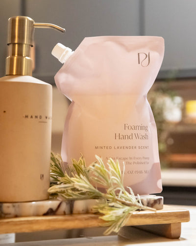 Foaming hand wash bottle and pump dispenser on a wooden tray with a blurred background