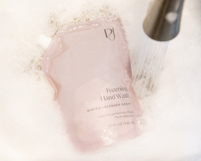 Pink foaming hand wash bottle with brand logo on a white background