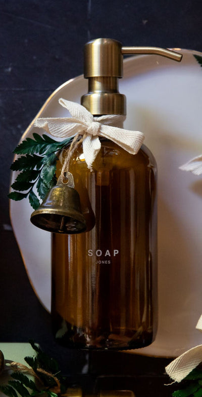 Decorative soap set with bottles, candles, and a plate on a dark surface