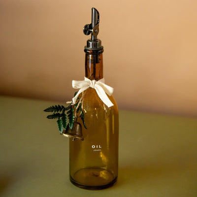 Brown glass oil bottle with a decorative cap on a beige background