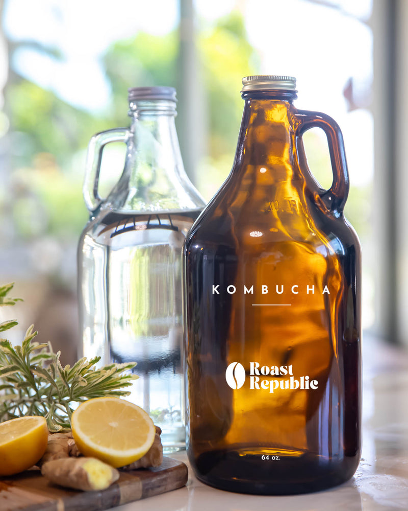 Two glass bottles with 'Roast Republic' branding on a table with lemons and herbs.