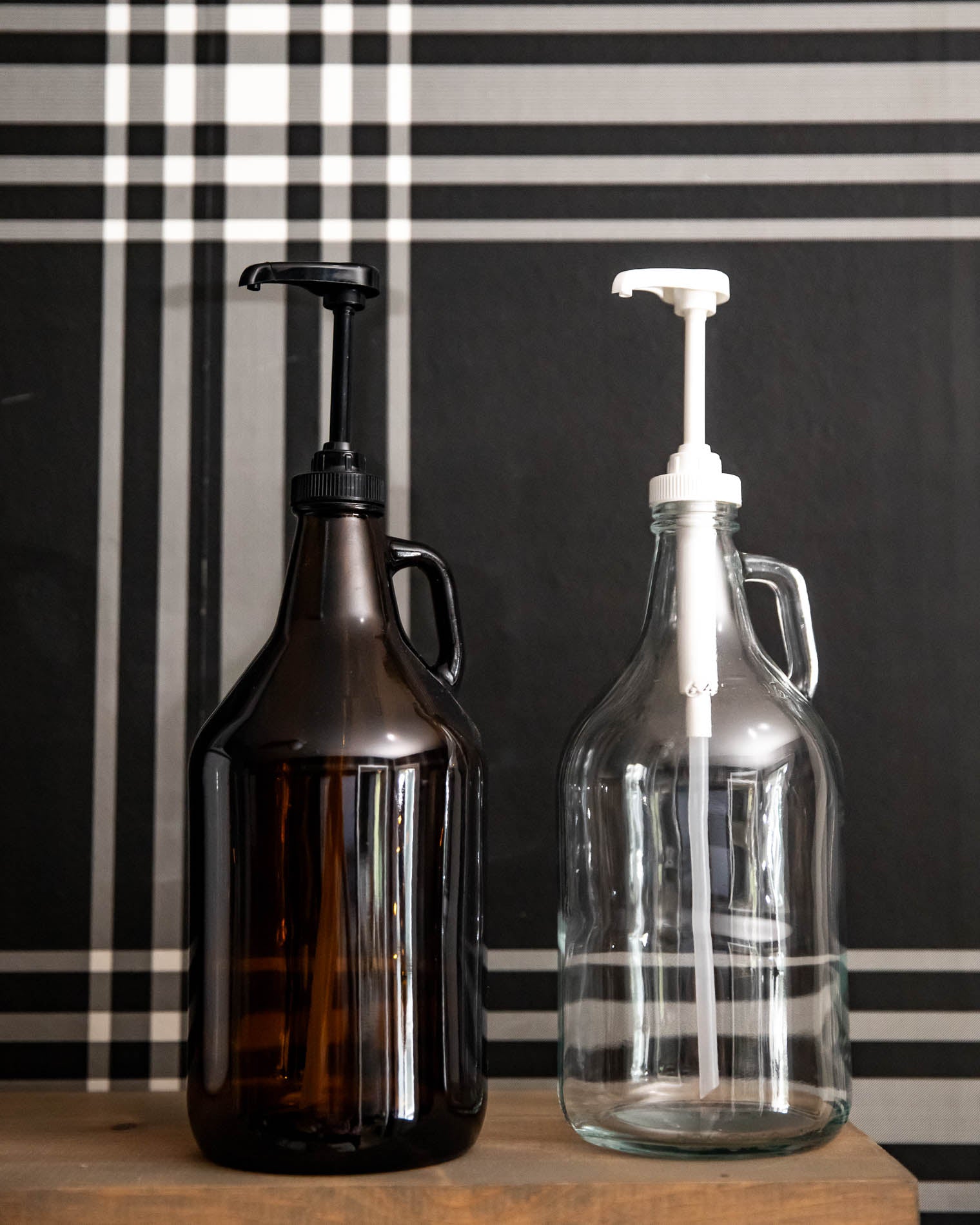Two glass bottles with pump dispensers against a black and white checkered background