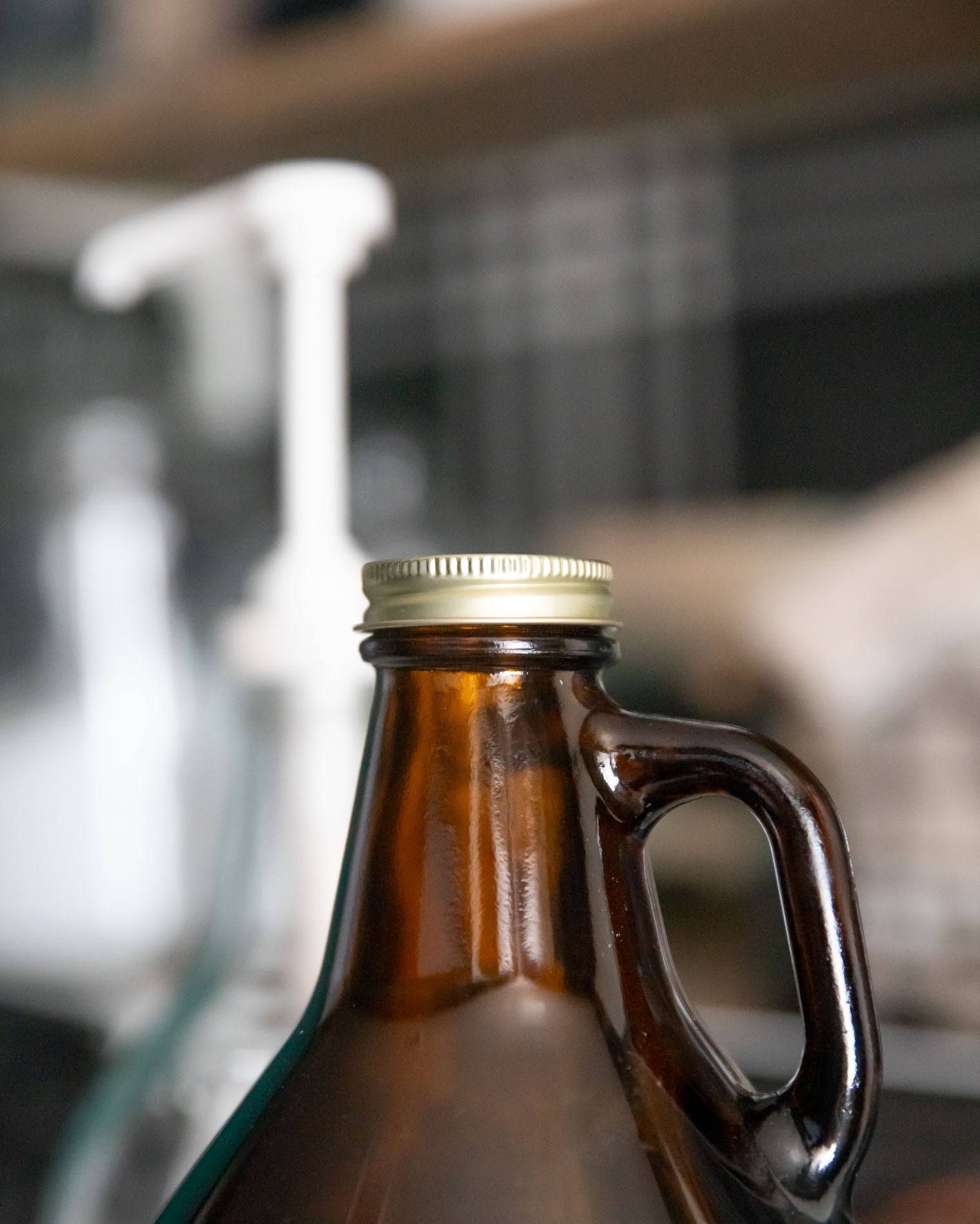 Brown glass bottle with a handle and metal cap on a blurred background