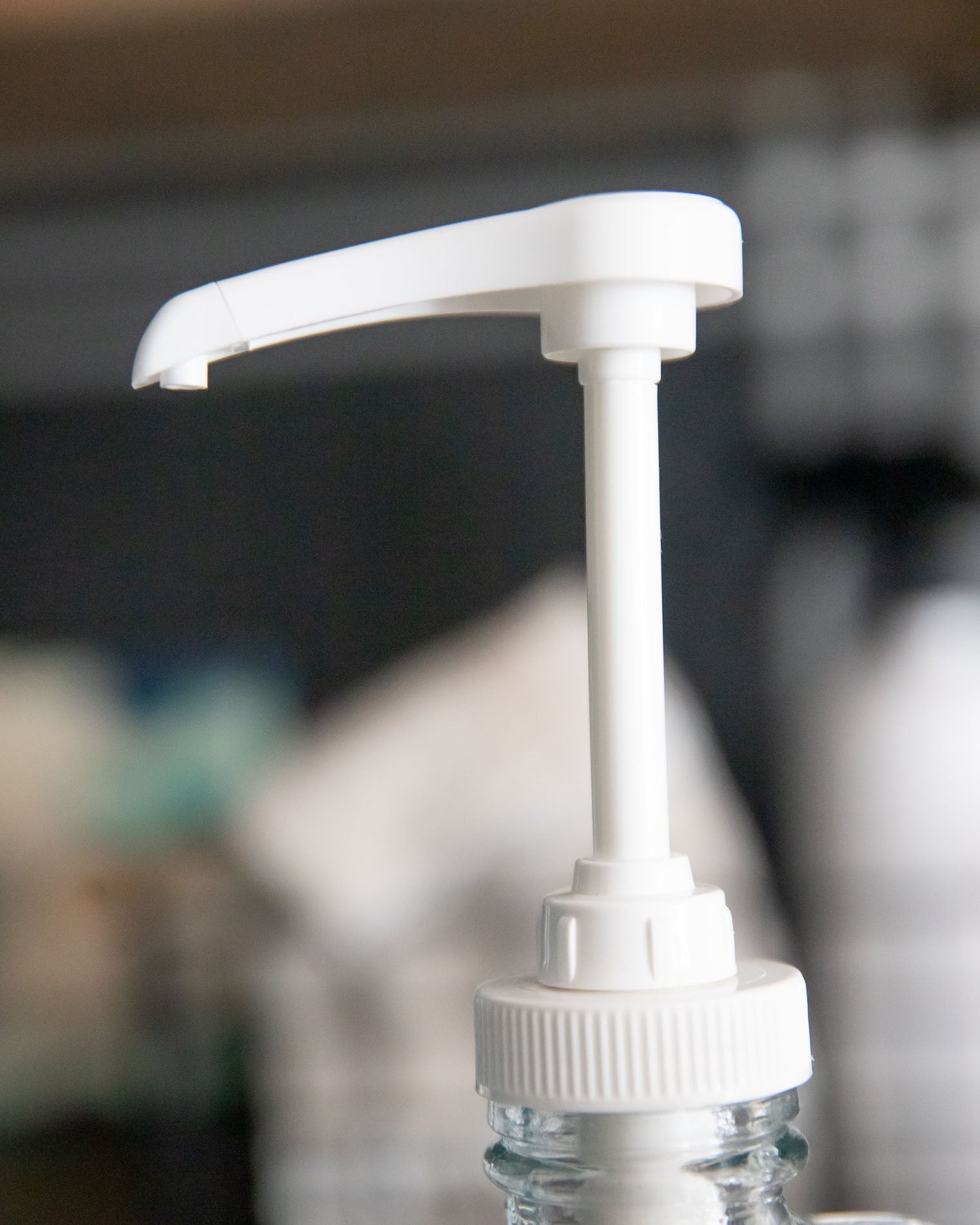 White pump dispenser on a glass bottle with a blurred background