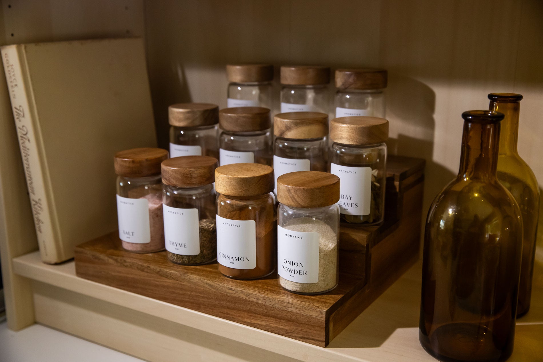 Collection of glass jars with wooden lids on a wooden shelf.