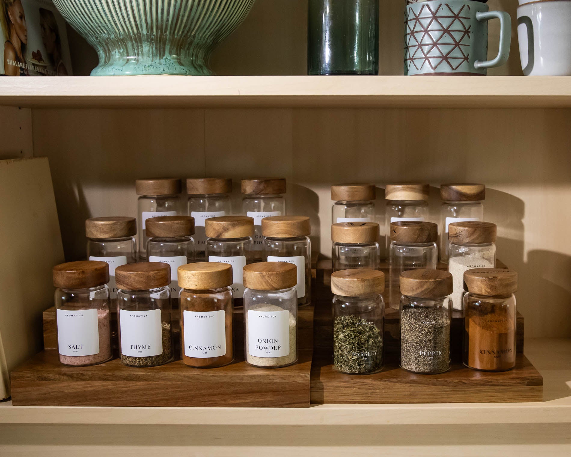 Spice jars with wooden lids on a extended shelf with a neutral background