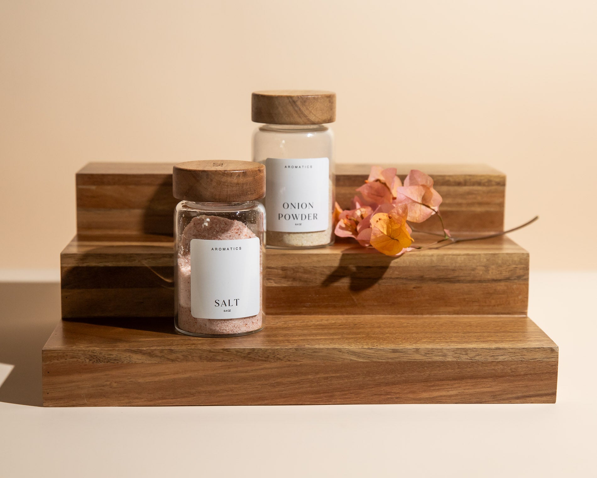 Waldorf spice jars labeled 'Salt' and 'Onion Powder' on a Acacia stand with a beige background.